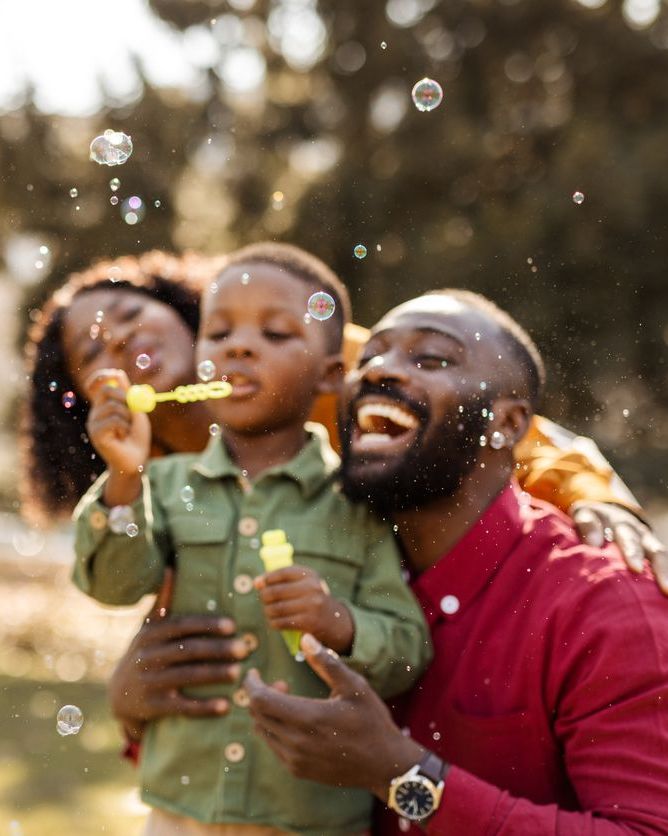 Happy African American Family Blowing Bubbles Outdoors